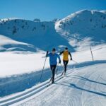Deux skieurs de fond en skating sur une piste enneigée en montagne