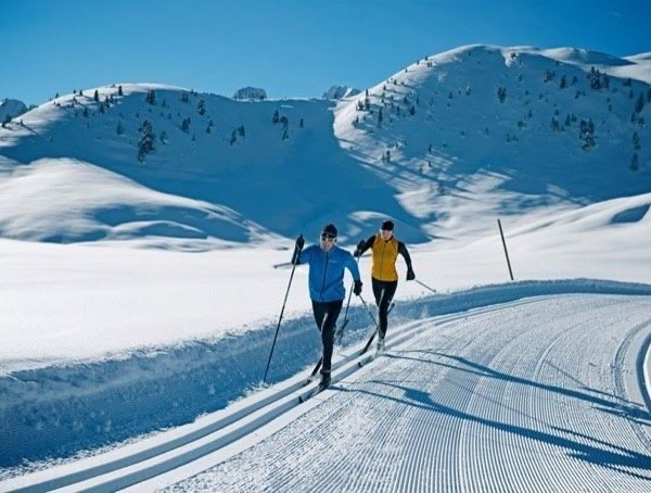 Deux skieurs de fond en skating sur une piste enneigée en montagne