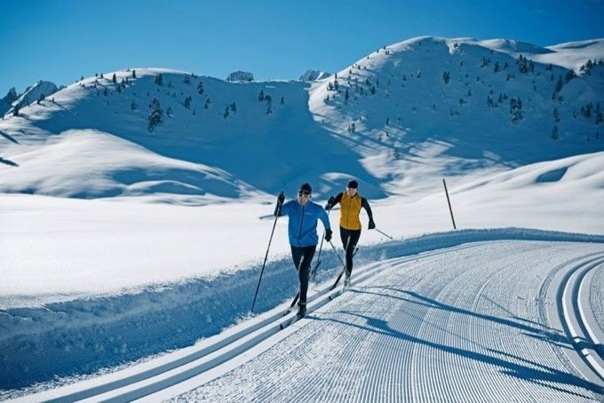 Deux skieurs de fond en skating sur une piste enneigée en montagne